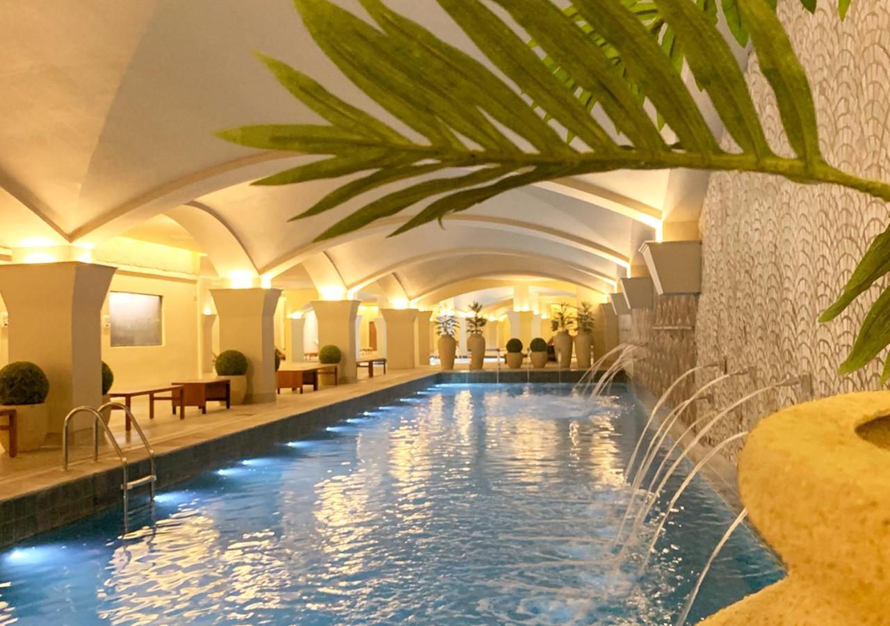 Buona Vitta Gramado Resort & Spa By Gramado Parks Buitenkant foto The photo shows an indoor swimming pool with a serene and elegant atmosphere. The pool has a calm blue water surface, illuminated by soft lights along its edges. The architectural design features arches in the ceiling, creating an open and spacious f