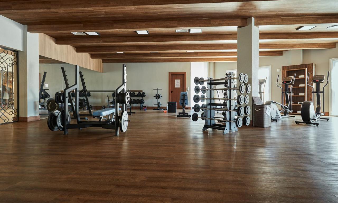 Buona Vitta Gramado Resort & Spa By Gramado Parks Buitenkant foto The photo shows a spacious gym with a wooden floor and wooden ceiling beams. Various pieces of gym equipment are visible, including weight benches and racks with weights. On one side, there are free weights organized on a rack, while other equipment 