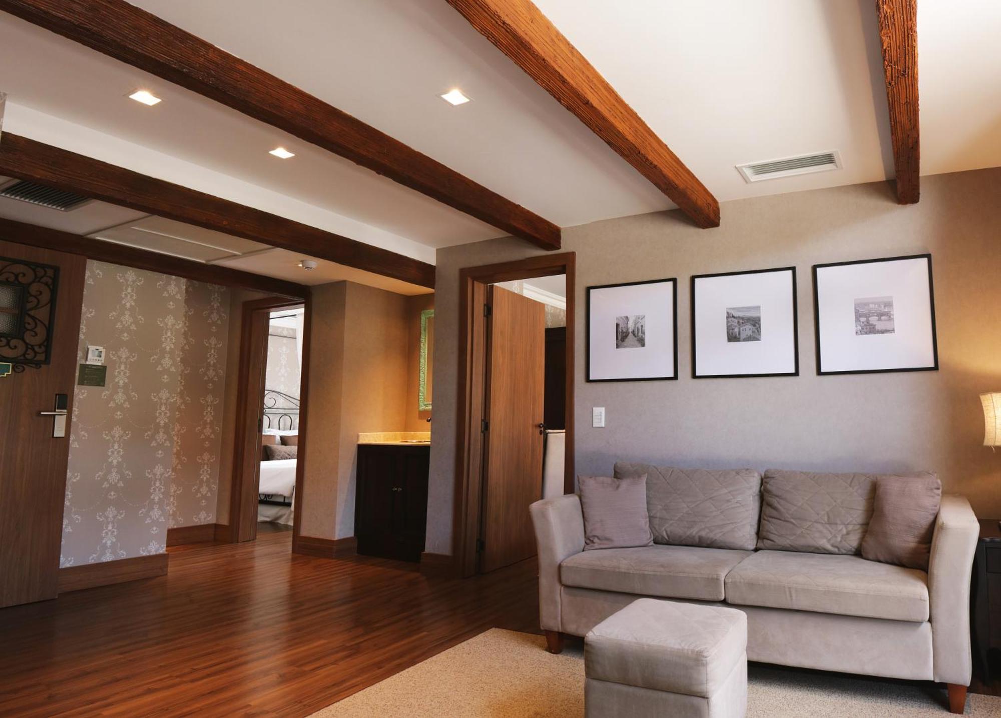 Buona Vitta Gramado Resort & Spa By Gramado Parks Buitenkant foto The photo showcases a modern living space with a cozy and well-lit atmosphere. There are wooden beams visible on the ceiling, adding a rustic touch. The flooring is a warm-toned wood, contributing to the inviting feel of the room. 

On one side, ther