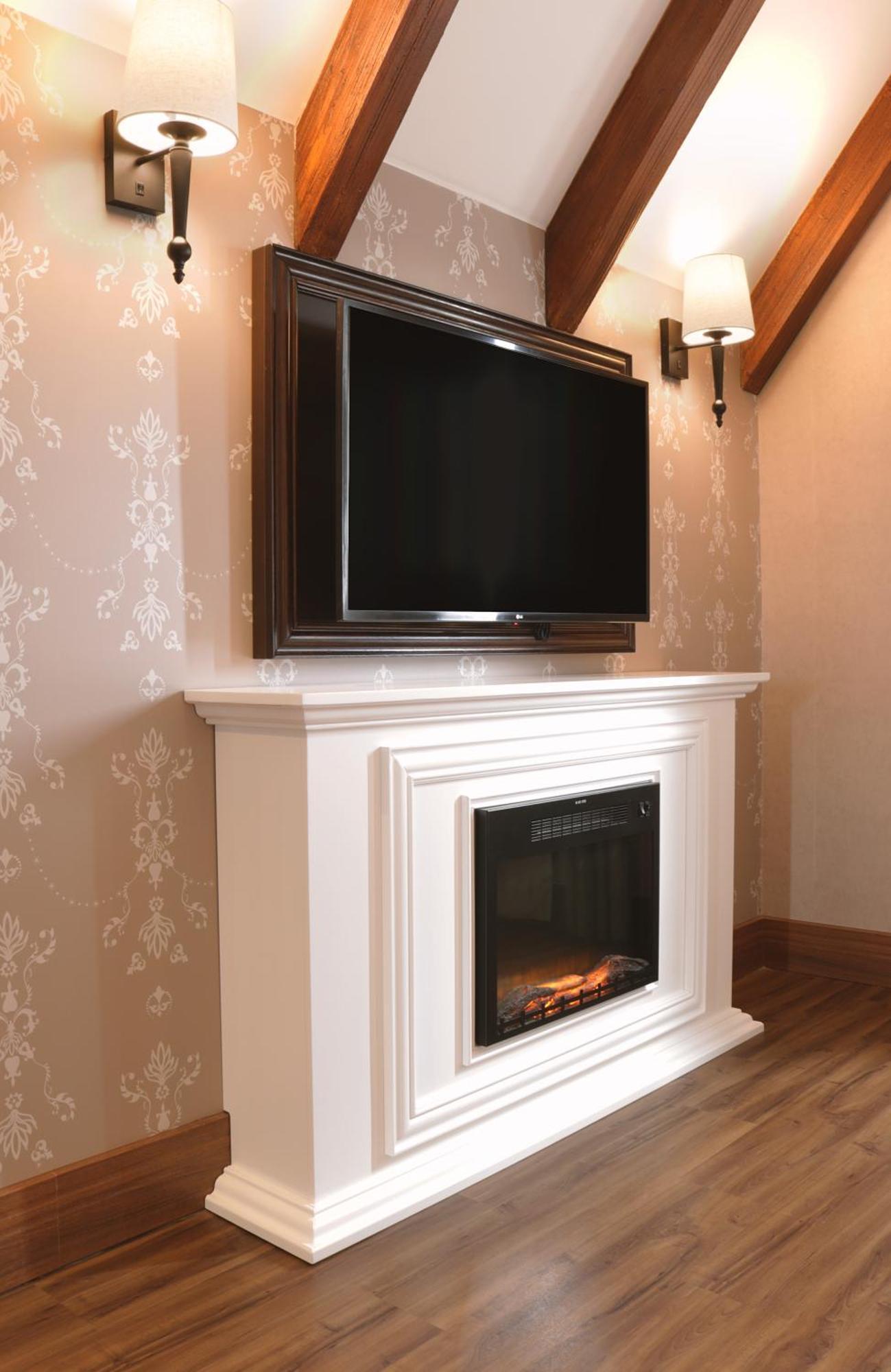 Buona Vitta Gramado Resort & Spa By Gramado Parks Buitenkant foto The image shows a modern living room setup featuring a white mantel with an electric fireplace. Above the mantel, there is a large flat-screen television mounted on the wall. The fireplace has a glass front and displays a realistic flame effect, crea